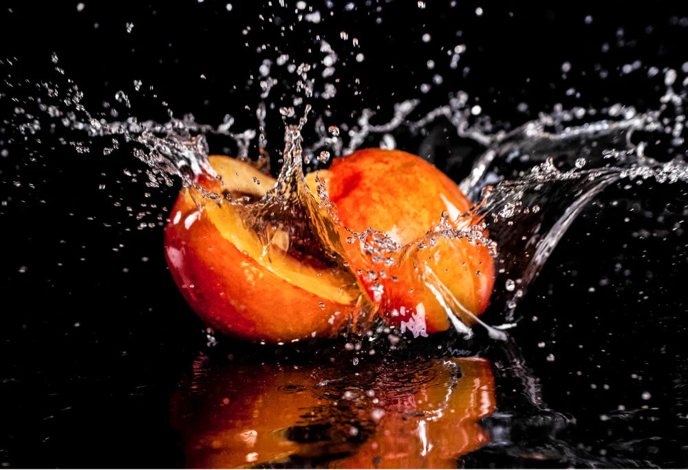 Two peaches splashing into water with a black background and 'Midwest Fragrance Company' logo.